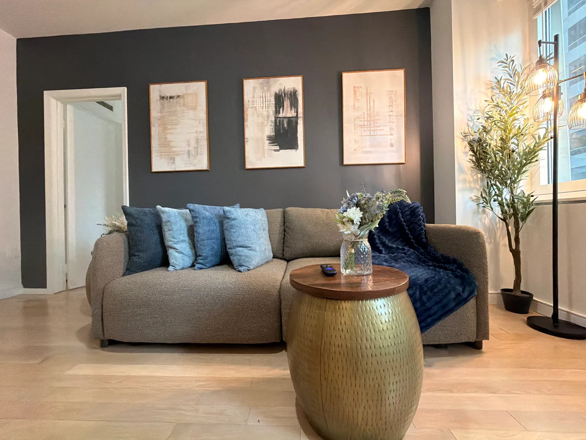 Sofa with blue cushions against a dark accent wall
