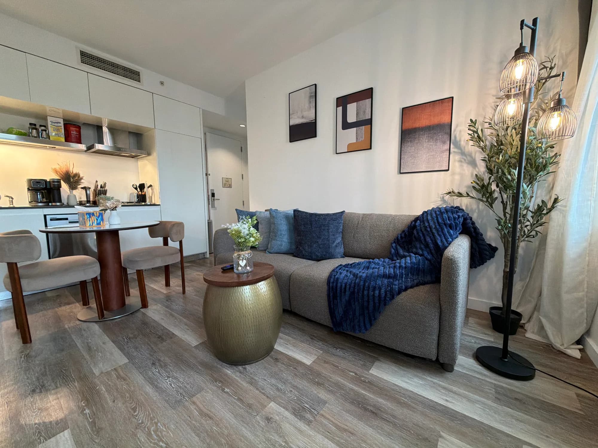 Blue sofa beside a round dining table and a white kitchen